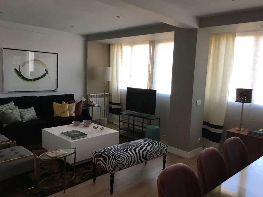 Salón reformado con suelo de madera y gran ventanal
